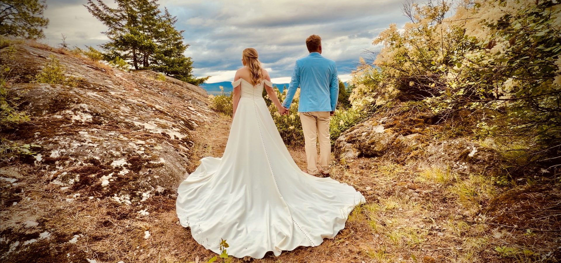 A bride and groom holding hands on a rocky hilltop in North Idaho